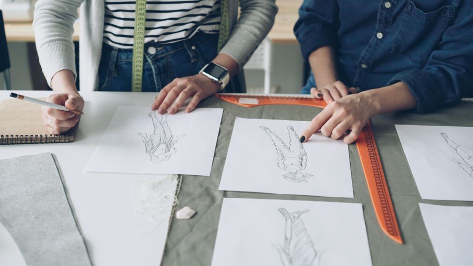 Designers working together on fashion sketches, coordinating design ideas.