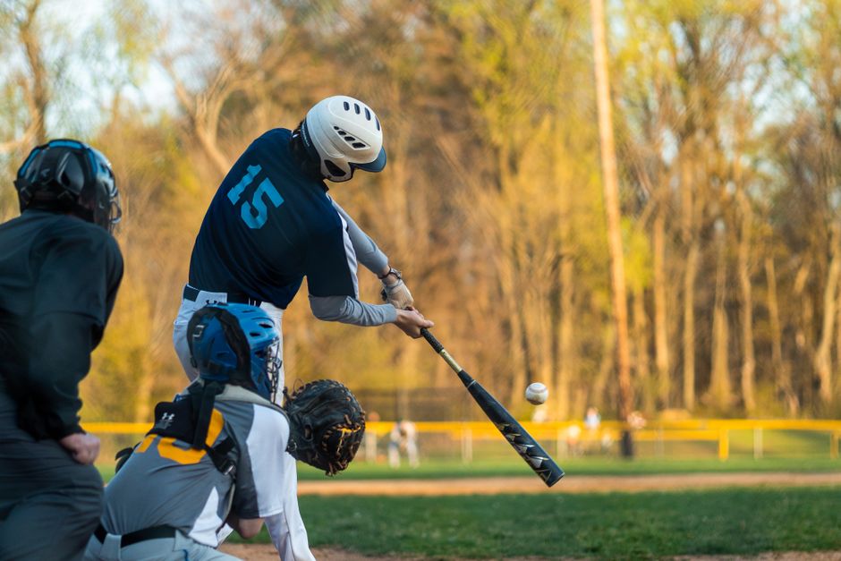 Baseball players in action on field, capturing the hit with batter, catcher, and umpire.